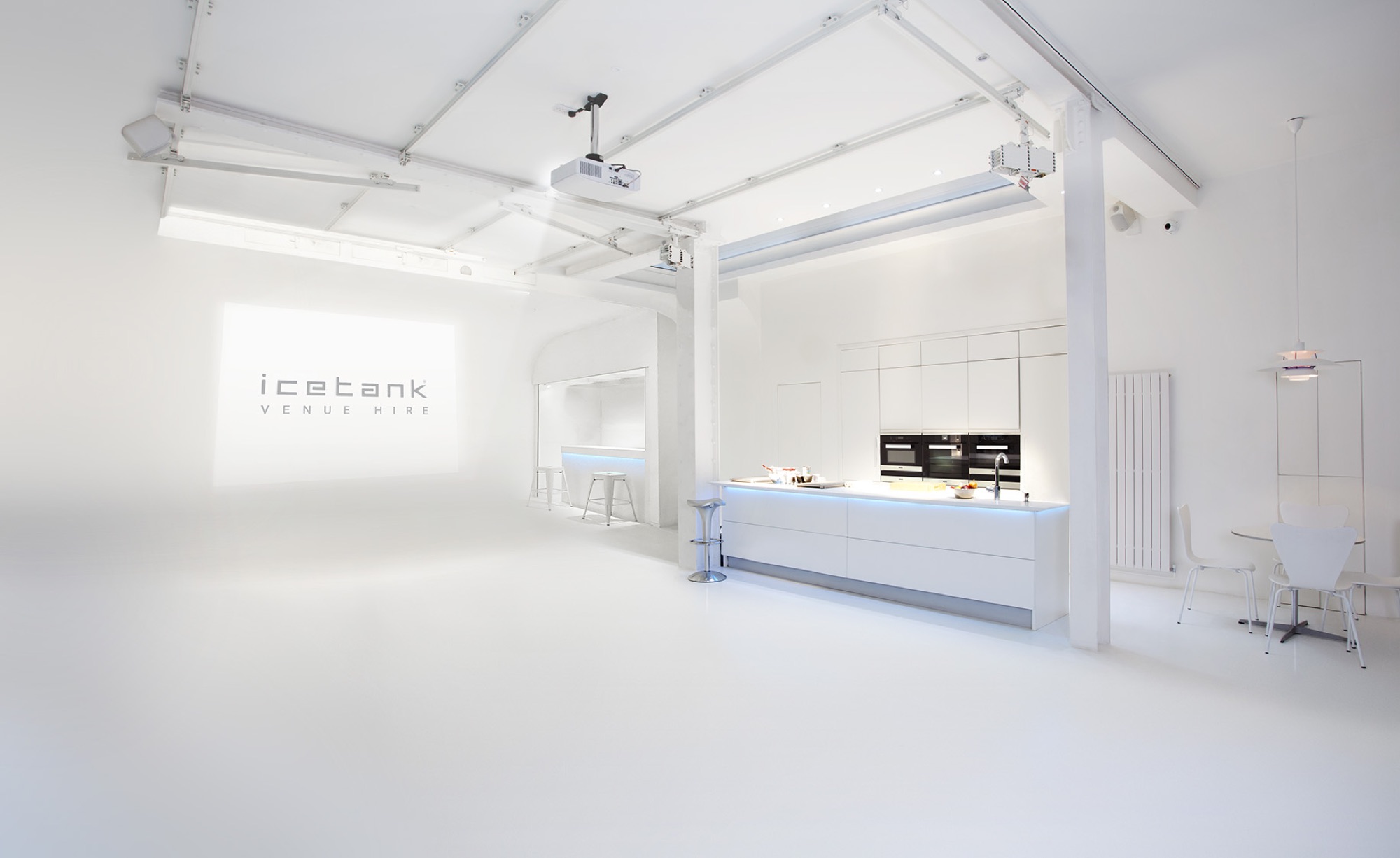 The white ground-floor room at ICETANK, daylight, the ICETANK name projected on the wall